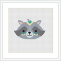 The image depicts a cross stitch pattern representing a stylized raccoon face with tribal-inspired geometric patterns, framed by a simple white square frame against a white background.