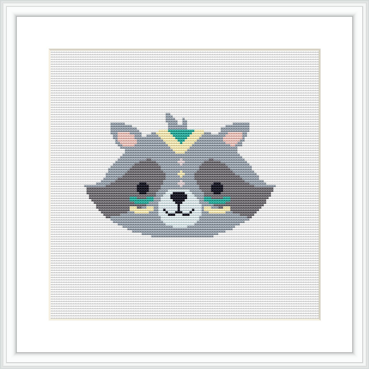 The image depicts a cross stitch pattern representing a stylized raccoon face with tribal-inspired geometric patterns, framed by a simple white square frame against a white background.