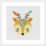 The image shows a framed cross stitch pattern of a stylized deer head with tribal decorations. It is centered on a white canvas background.