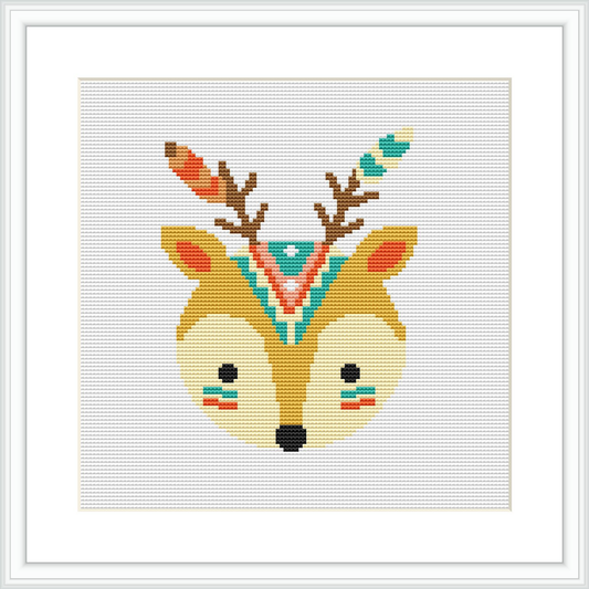 The image shows a framed cross stitch pattern of a stylized deer head with tribal decorations. It is centered on a white canvas background.