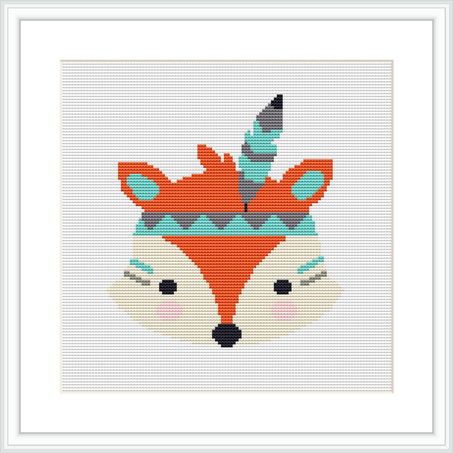 The image showcases a framed cross stitch pattern of a stylized fox head with tribal patterns and feather adornments against a white background.