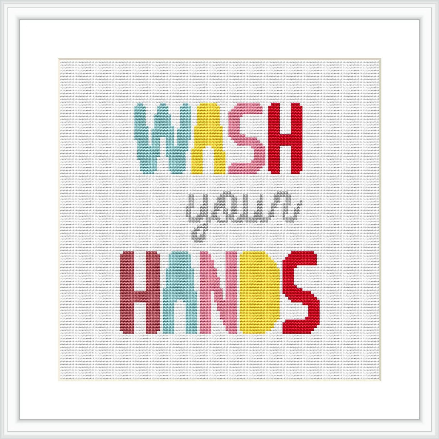 The image displays a cross stitch design framed in a white frame. The design features the phrase 'WASH your HANDS' in bold, block letters with each word in a different pastel color. The background appears to be white or off-white fabric.