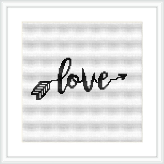 The image depicts a framed cross stitch pattern representing the word 'love' written in a cursive, calligraphic style with the last 'e' extending into an arrow. The pattern is monochrome, stitched with black thread on a white evenweave fabric.