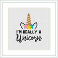 The image is a digital mock-up of a cross-stitch pattern within a square frame. It features a graphic of a unicorn's horn and ears, with colorful stars around, and a cursive typography that states 'I'm really a unicorn'.