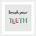 The image shows a framed cross stitch design with the phrase 'Brush your TEETH' where 'TEETH' is written in colorful block letters and 'Brush your' in a simple black font, all on a plain white canvas.