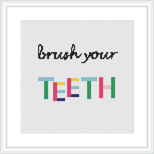 The image shows a framed cross stitch design with the phrase 'Brush your TEETH' where 'TEETH' is written in colorful block letters and 'Brush your' in a simple black font, all on a plain white canvas.