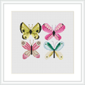 The image presents a framed cross stitch tapestry depicting four distinct butterflies. They are arranged in a two-by-two grid against a plain, lightly speckled background. Each butterfly is stitched in different pastel colors with a slight gradient effect.