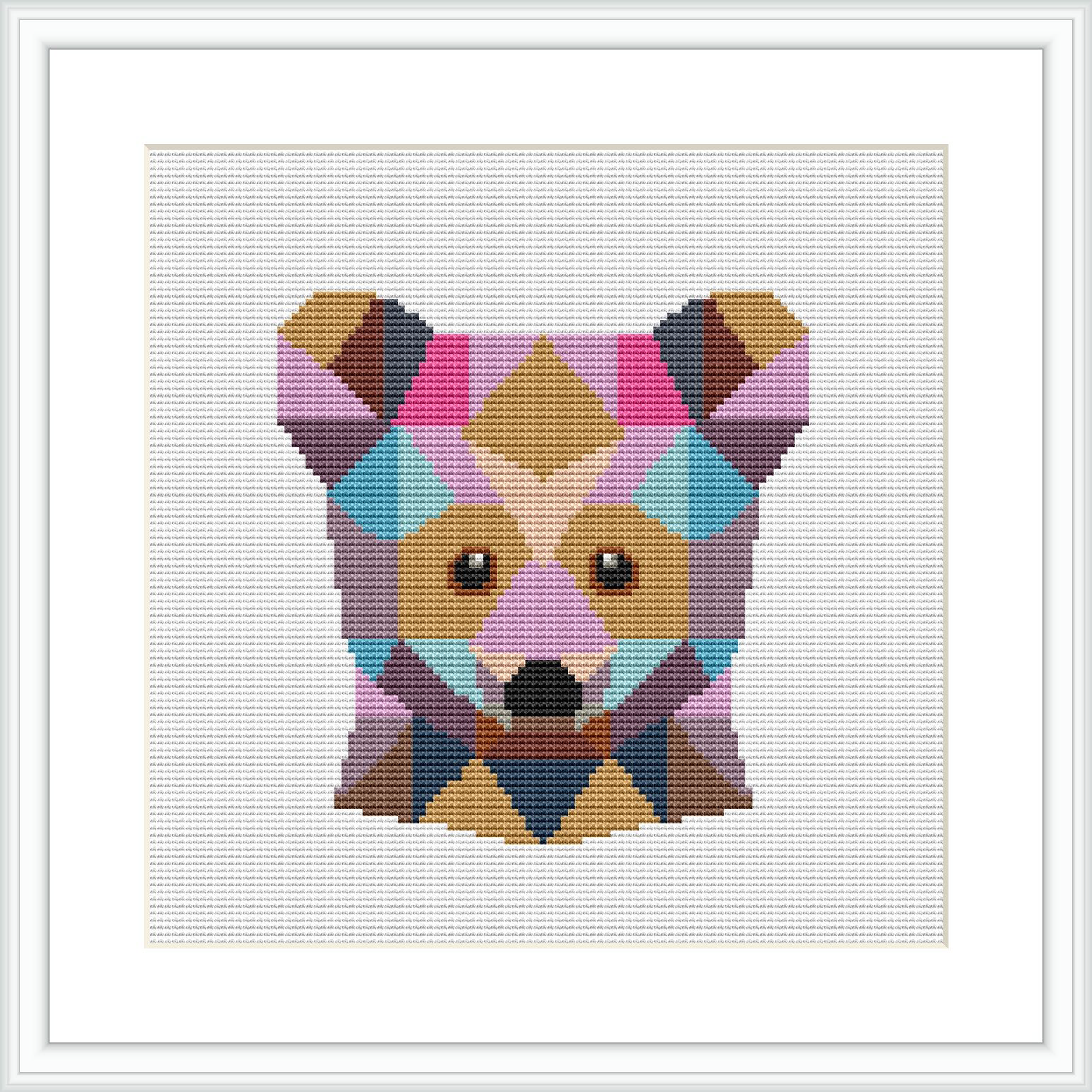 The image shows a framed cross stitch pattern of a bear's face, composed of various geometric shapes in a range of pastel colors. The pattern is centered and showcased within a square frame against a white background.