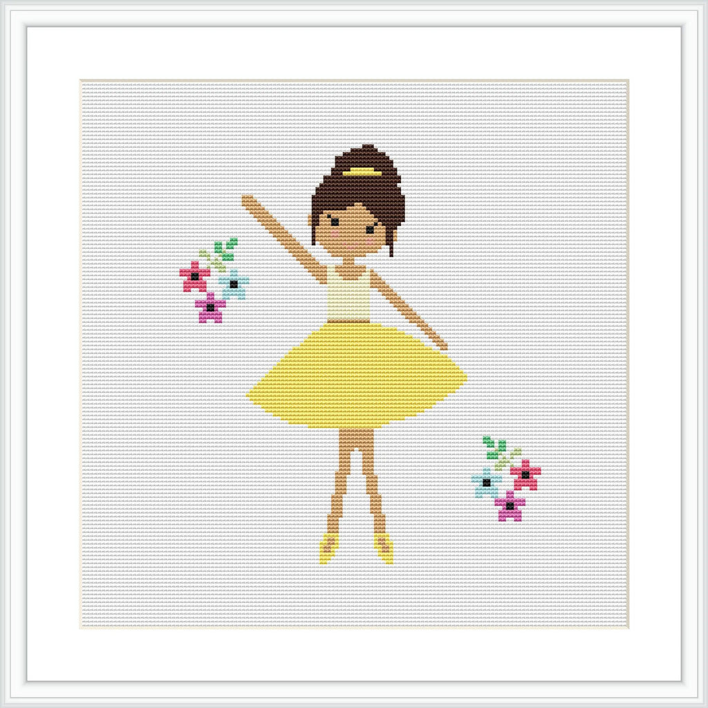 The image features a cross stitch pattern of a ballerina in a yellow dress, with her arms raised gracefully. She is wearing brown ballet shoes and has her hair up in a bun. There are colorful flowers to her right and left on a white background. The overall scene is framed with a simple white border.