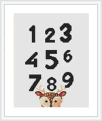 The image shows a cross stitch pattern with the numbers 1 through 9 arranged in three rows. Each number is in black on a white background, and at the bottom is the image of a giraffe's face peeking out, with its eyes, ossicones (horn-like structures), and a small part of the neck visible.