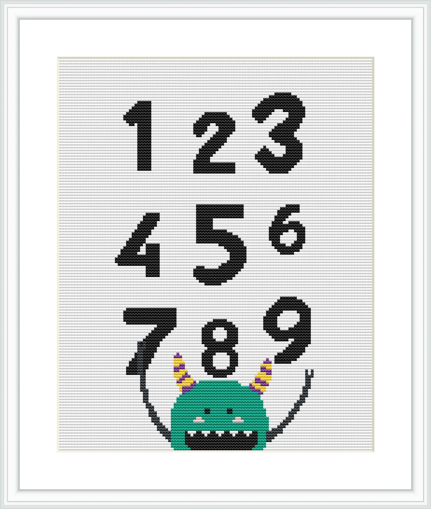 The image depicts a simple cross stitch pattern featuring a green cartoon monster sitting at the bottom, with some of its horns visible. Above the friendly monster, numbers one through nine are embroidered in a large font, occupying most of the crafted area.