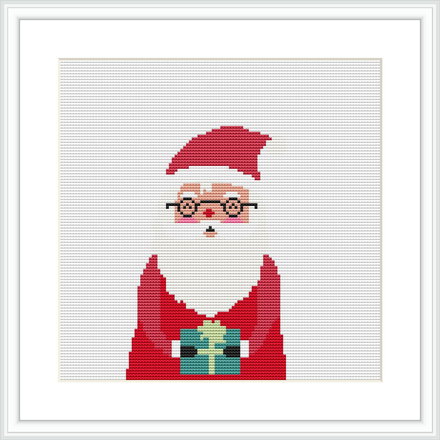 The image portrays a cross stitch pattern of Santa Claus from the chest up, wearing his iconic red hat and suit. He has circular glasses perched on his nose and is holding a green-wrapped Christmas gift with a golden ribbon. The background is plain, highlighting Santa and the gift.