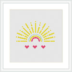 The image displays a framed cross stitch pattern design of a semi-circular sun with yellow rays extending outward at the top and three heart-shaped pink flowers at the bottom, all against a white background.