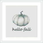 The image depicts a cross stitch pattern of a stylized green and white pumpkin below which the phrase 'Hello Fall' is stitched in a simple, readable font. The design is centered on a grid-like fabric, framed within a minimalist square frame, illustrating a calming autumn motif.