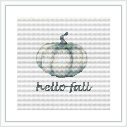 The image depicts a cross stitch pattern of a stylized green and white pumpkin below which the phrase 'Hello Fall' is stitched in a simple, readable font. The design is centered on a grid-like fabric, framed within a minimalist square frame, illustrating a calming autumn motif.