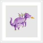 The image depicts a stylized purple dragon with green accents on its wing tips and tail, as well as a yellow snout, playfully standing against a plain white background within a framed cross stitch pattern.