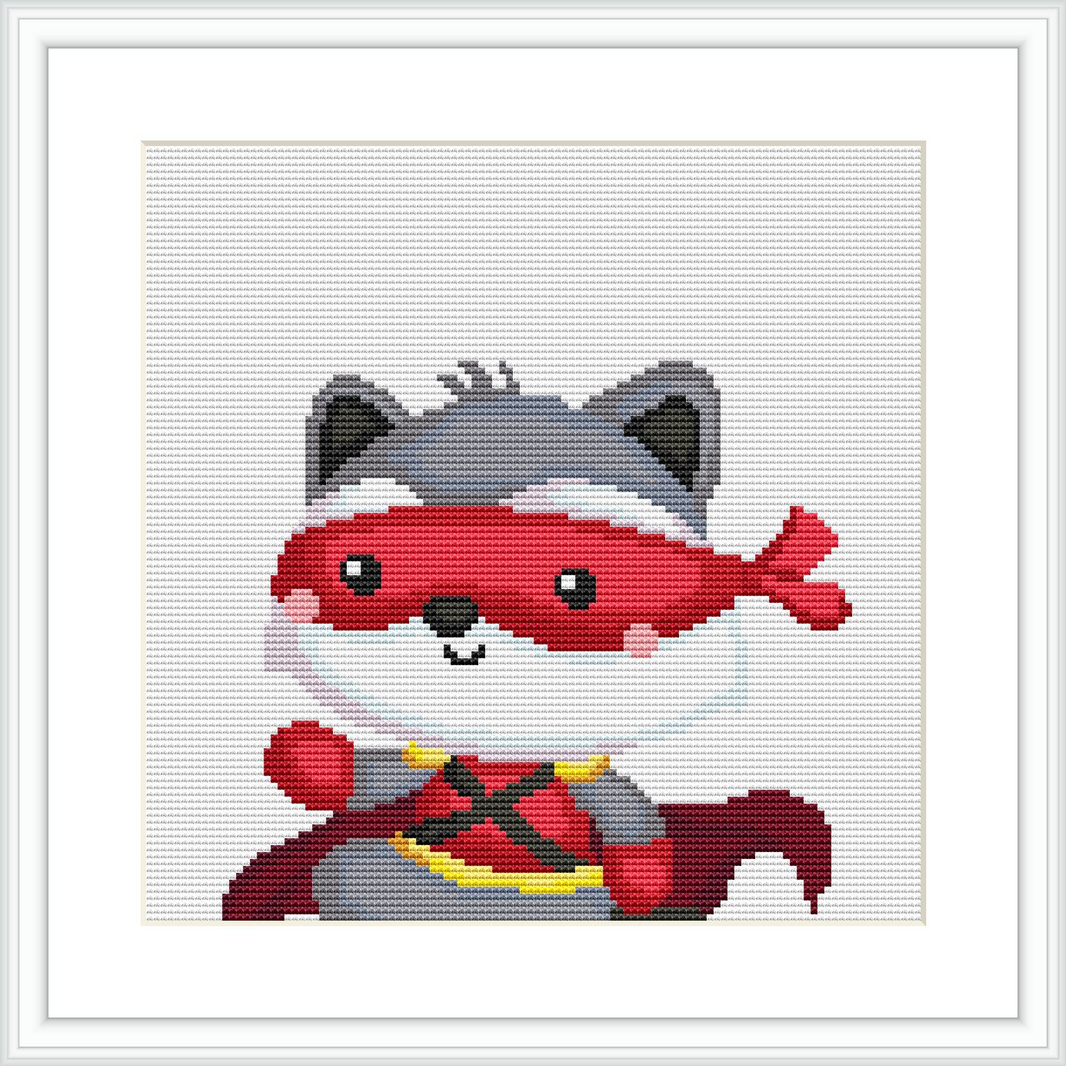 The image features a cross stitch pattern of a cartoon-style raccoon dressed as a superhero. The raccoon has a mask, cape, and is striking a heroic pose.
