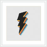 The image displays a cross stitch pattern framed and mounted on a wall. The pattern consists of a stylized silhouette of a face in profile outlined in black and segmented with stripes of bright yellow, orange, and blue against a white background.