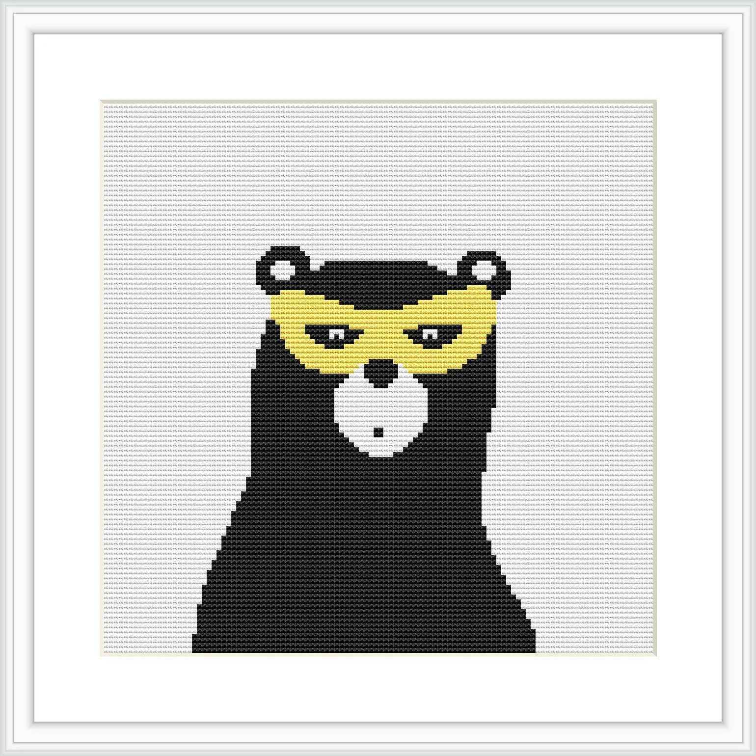 The image features a cross stitch pattern of a black bear with a superhero mask. The bear is primarily black with a white snout and yellow elements around the eyes. The pattern is square, displayed within a white frame on a plain background.