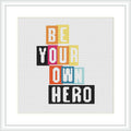 The design features the phrase 'BE YOUR OWN HERO' in block letters of varying colors, centered against a light background within a white square frame.