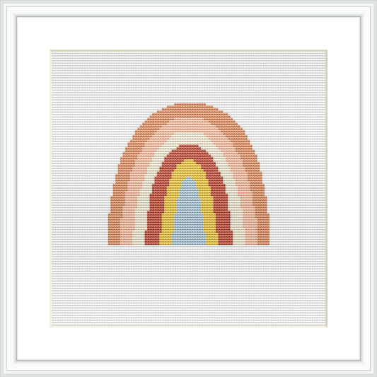 A framed cross stitch pattern depicting an abstract, stylized rainbow with layered arches in various neutral and earthy colors on a white field. The design is presented within a square frame on a white background.