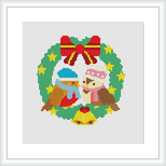 The image displays a cross stitch pattern depicting two birds, one wearing a Santa hat and the other with a blue hat, inside a Christmas wreath adorned with red ribbon, yellow stars, and tiny red ornaments, all on a white background.