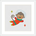 The image showcases a cross stitch pattern depicting a cartoon-like monkey in a red and green spacesuit, surrounded by a light blue halo representing space. There are small yellow and red stars scattered around the monkey.