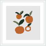 The image shows a cross stitch pattern featuring three Valencia oranges with green leaves. Two oranges are whole and one is cut, with all pieces placed against a white background within a square frame.