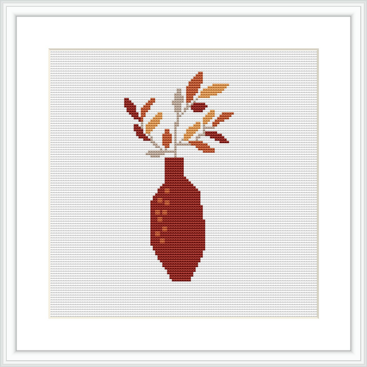 A digitally rendered cross stitch pattern of a terracotta vase with a patterned design and branches with leaves inside it, all framed on a white background.