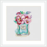 The image shows a cross stitch pattern of a perfume bottle with blooming flowers arranged on top. The bottle and flowers are highly stylized, with the stitching providing texture and depth to the design.