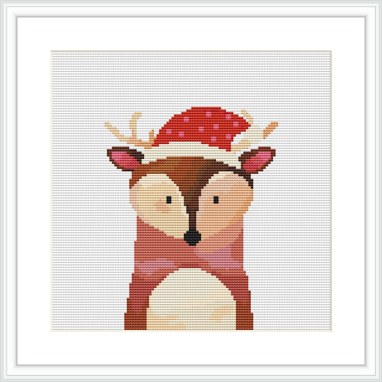 The image shows a framed cross stitch pattern of a stylized deer wearing a Santa hat. The deer is centered on the canvas with a simple, illustrative design emphasizing bold colors and pixel art aesthetic.