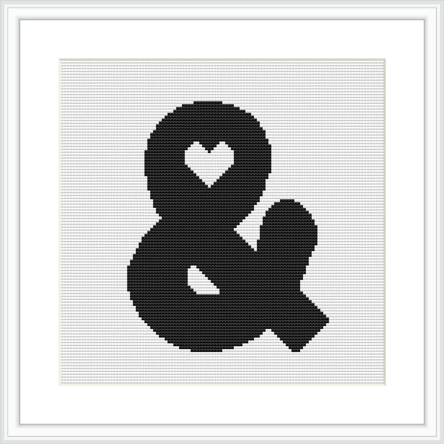 The image depicts a framed cross stitch pattern showcasing the ampersand '&' character with a simple heart shape incorporated into its upper loop. The design is stitched in black on a white canvas and is centered within the frame.