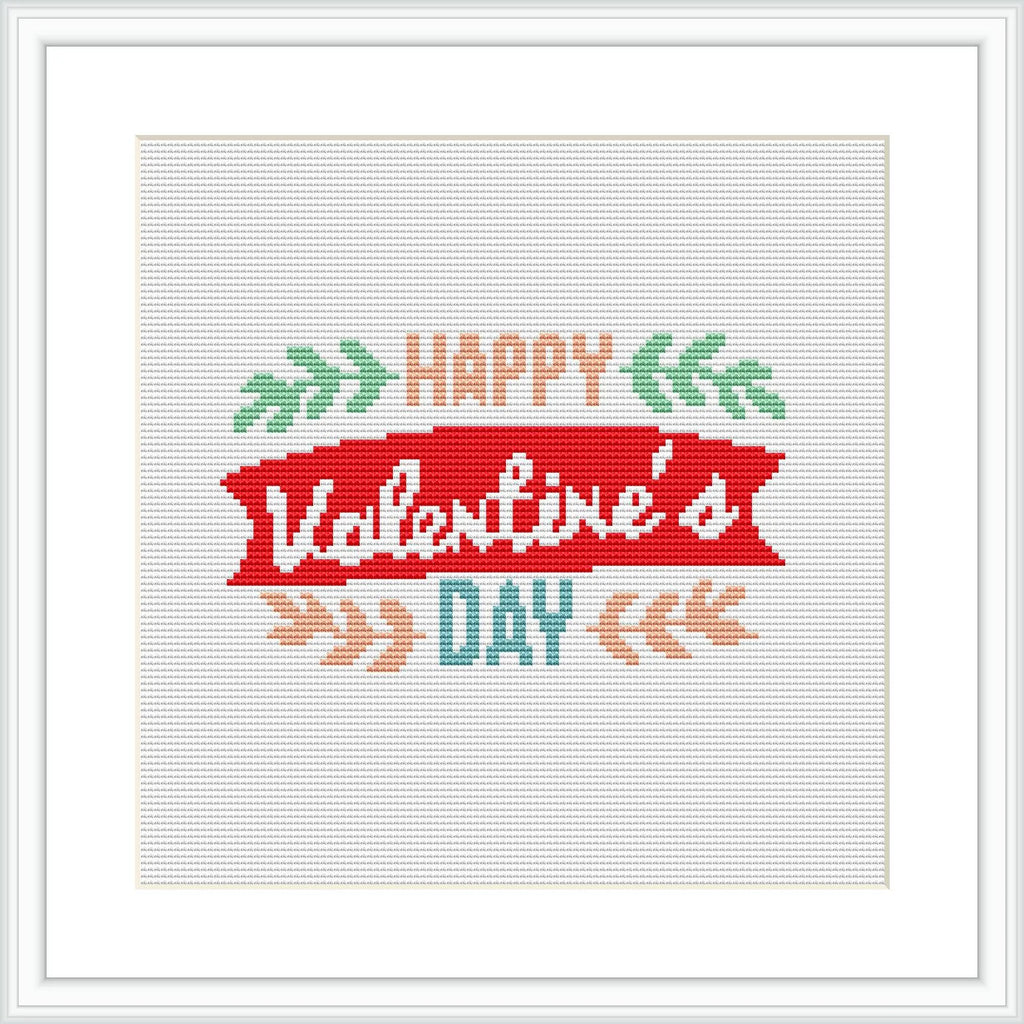 The image showcases a square cross-stitch pattern featuring a stylized banner with the text 'Happy Valentine's Day' surrounded by decorative elements like foliage and arrows.