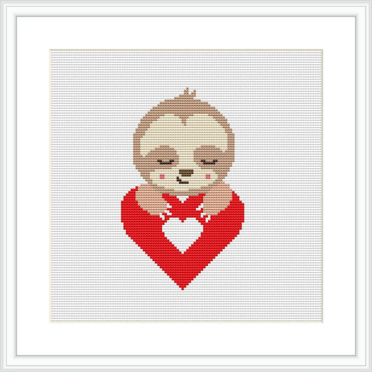 The image shows a cross stitch design featuring a cute sloth wrapped around a red heart, positioned against a plain white background. The design is neatly framed, suggesting presentation as a finished piece.