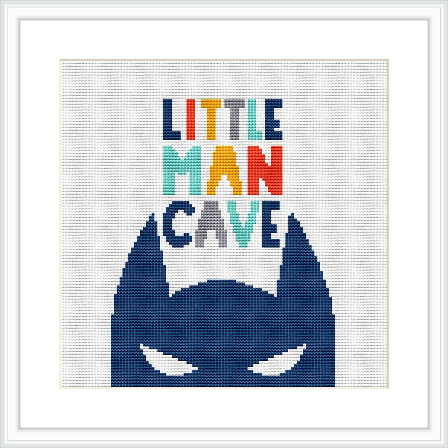 The image features a cross stitch pattern with the phrase 'LITTLE MAN CAVE' in colorful block letters at the top and the silhouette of a stylized superhero mask in blue at the bottom, all centered against a white background within a frame.