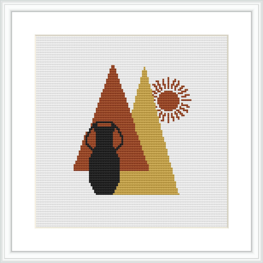 The image shows a cross-stitch pattern with a black vase set against a background of overlapping geometric triangles in red and mustard yellow. To the right, there's a sunburst pattern in a circular shape resembling a stylized sun or flower.