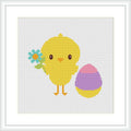 The image depicts a cross stitch pattern featuring a cartoon-like chick in yellow standing beside a multicolored Easter egg with purple at the base and pink at the top. The chick is holding a small bunch of blue flowers in one 'wing'. The pattern is displayed on a white background, simulated to represent aida cloth.