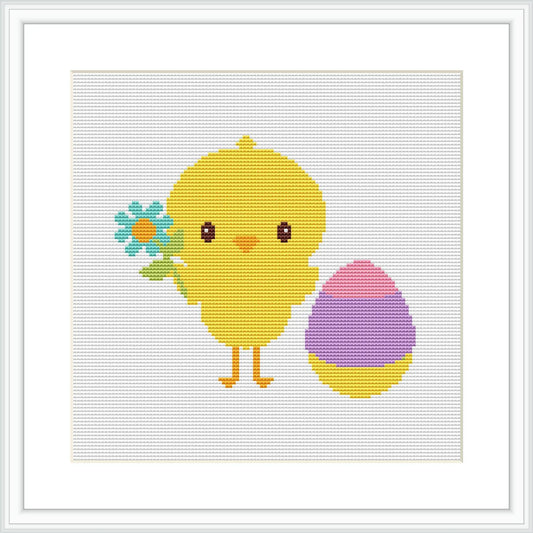 The image depicts a cross stitch pattern featuring a cartoon-like chick in yellow standing beside a multicolored Easter egg with purple at the base and pink at the top. The chick is holding a small bunch of blue flowers in one 'wing'. The pattern is displayed on a white background, simulated to represent aida cloth.