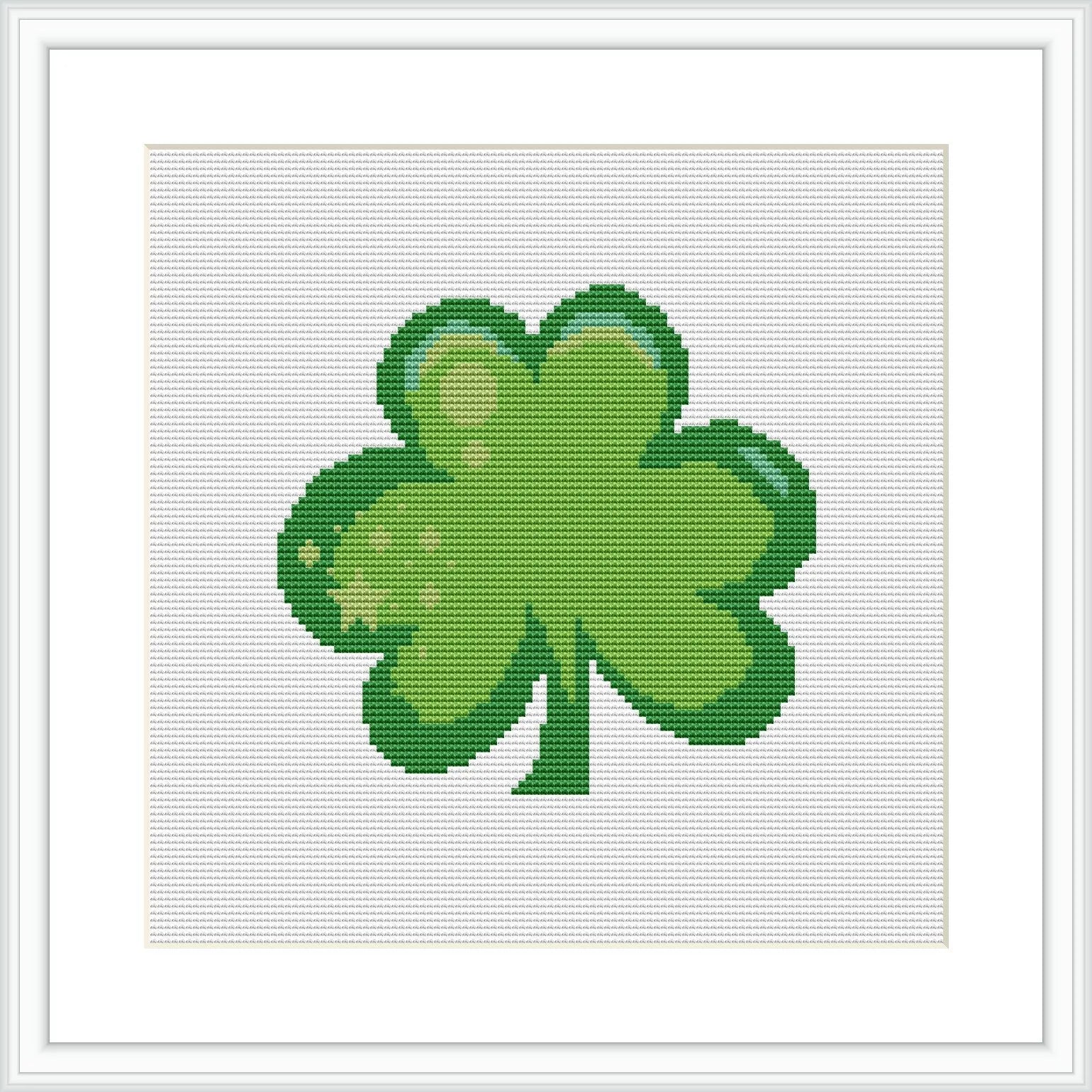 A cross stitch pattern featuring a green four-leaf clover centered on a white background, framed in a simple square pattern.