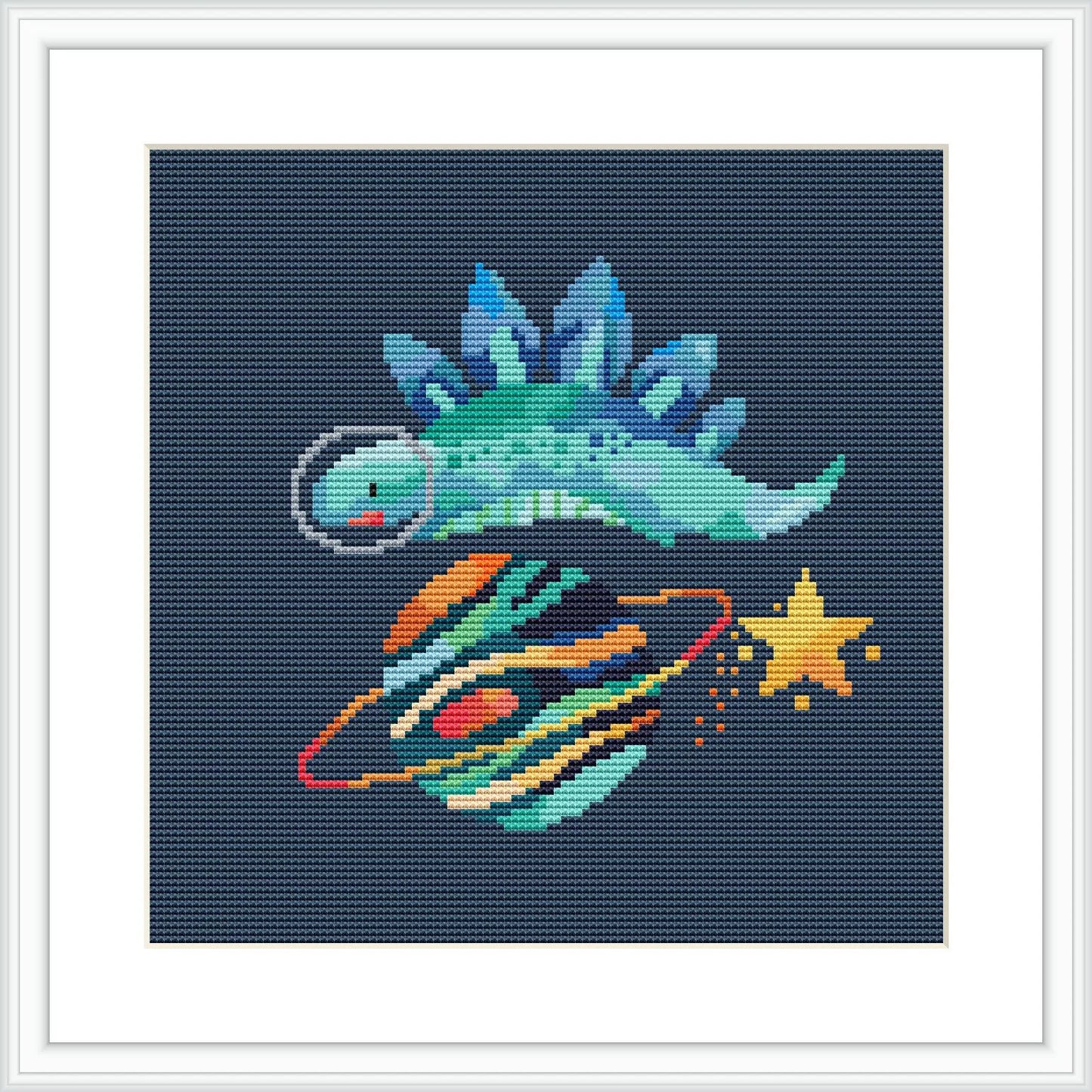 The image features a stylized dinosaur with space elements, including rockets and stars, composed in cross stitch on a dark blue background, framed in white.