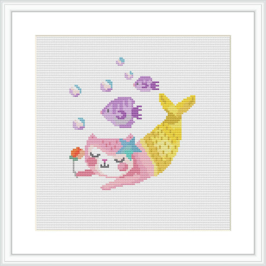 The image portrays a cross stitch pattern of a cat with mermaid features, including a fish tail, on a white canvas. There are colorful bubbles and fish surrounding the cat mermaid, with a predominance of pink and yellow hues.