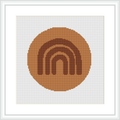 The image depicts a square cross stitch pattern featuring a monochromatic circular arc motif centered within a square frame. The design is composed of earthy brown shades against a white background.