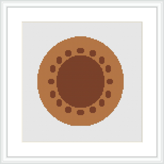 The image showcases a cross stitch pattern depicting an abstract, geometric circle centered on a white background, framed by a simple white frame.