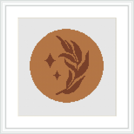 The image features a cross stitch pattern framed in white, showcasing a simple plant design and small stars on a monochromatic brown circle, set against a white background.