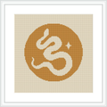 The image showcases a framed cross stitch pattern featuring a stylized monogram of the letter 'E' centered on a yellow circular background bordered by beige. Star-like and dot embellishments surround the letter.