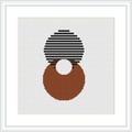 The image shows a framed cross stitch pattern with a white background, featuring an abstract design composed of two overlapping circles, one on top of the other rendered in stripes of black and white, and the other solidly filled with shades of brown placed on a grid indicative of a 112 by 112 stitch count.
