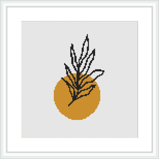 The image depicts a cross-stitch pattern featuring a stylized plant with long narrow leaves protruding from a round mustard yellow vase. The design is presented on a square grid, surrounded by a white border within a black frame.