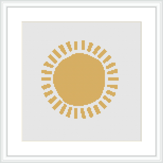 The picture shows a framed cross stitch pattern, placed against a white background. Centered on the canvas is a stylized sun with a solid round center in shades of yellow and gold, surrounded by rays represented by lines and geometric shapes.