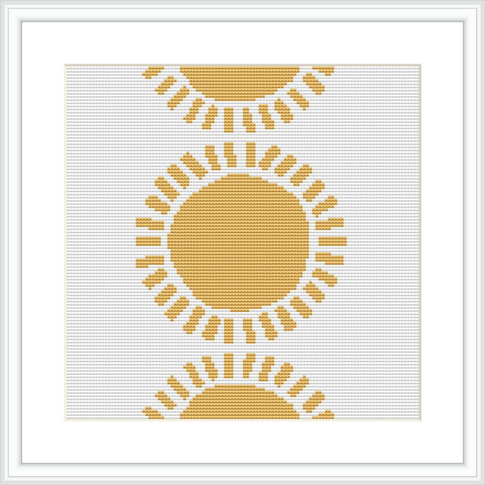 The image presents a cross stitch pattern featuring a central circular motif representing the sun, surrounded by emanating rays. The design is rendered in shades of yellow and white, creating a radiant appearance.