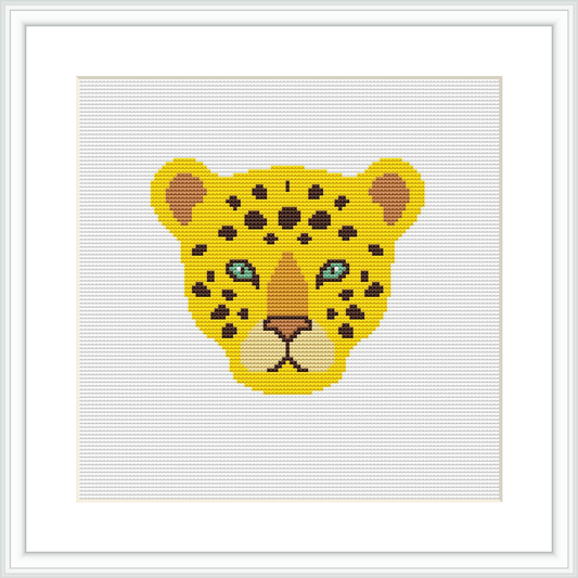 The image shows a cross stitch pattern of a leopard's face centered within a square canvas, framed by a simple white border. The leopard's eyes are highlighted in aqua, contrasting the yellow and black-spotted fur.